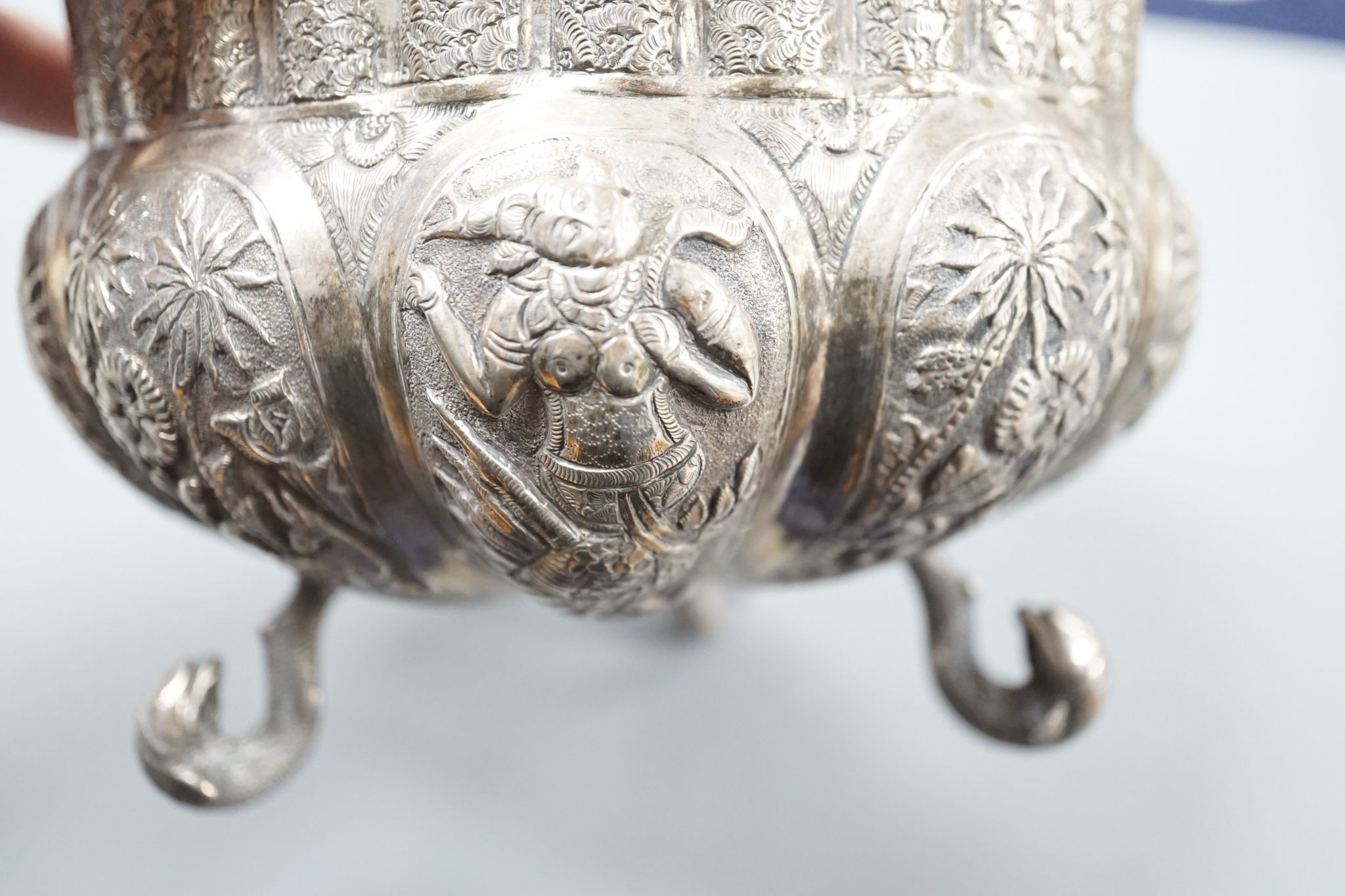 An Indian embossed white metal bowl, on three dolphin feet, diameter 13cm, 10oz.